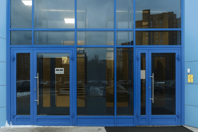 Фасад здания с алюминиевыми окнами и дверями, окрашенными порошковой краской в синий цвет
